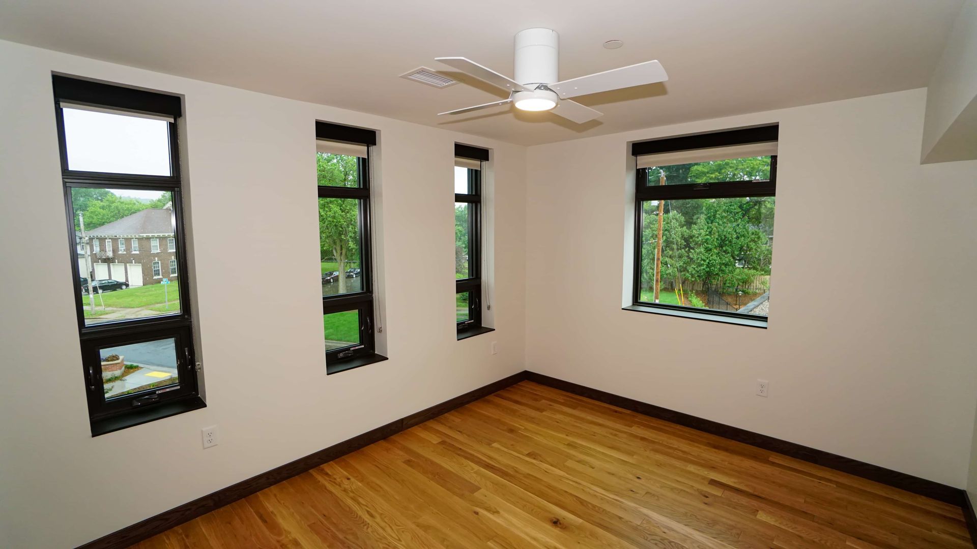 An empty room with hardwood floors and a ceiling fan.