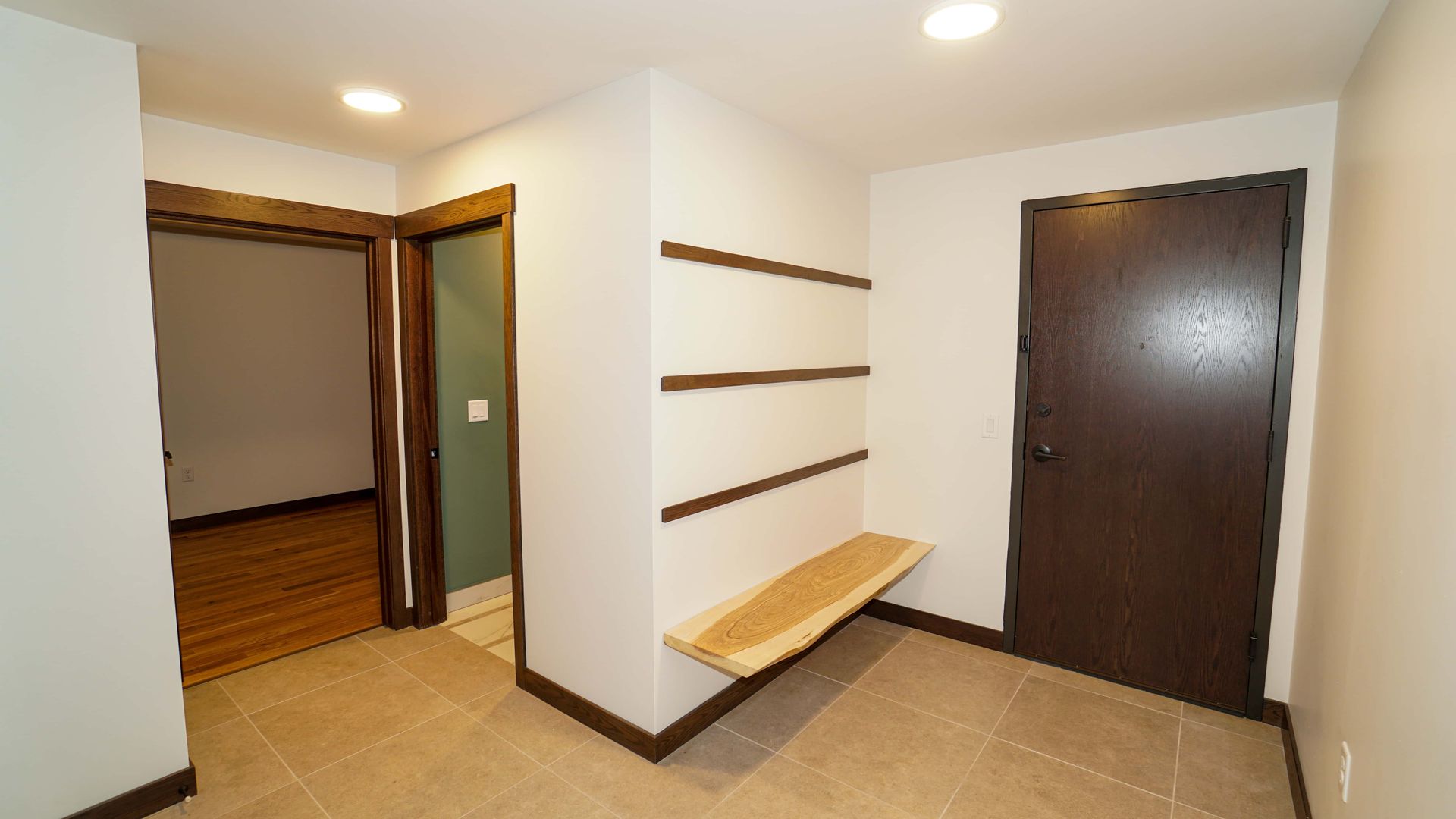 An empty hallway with a wooden bench and a door.
