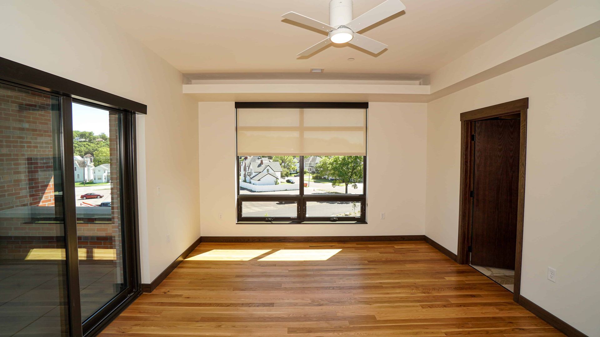 An empty room with hardwood floors and a ceiling fan.