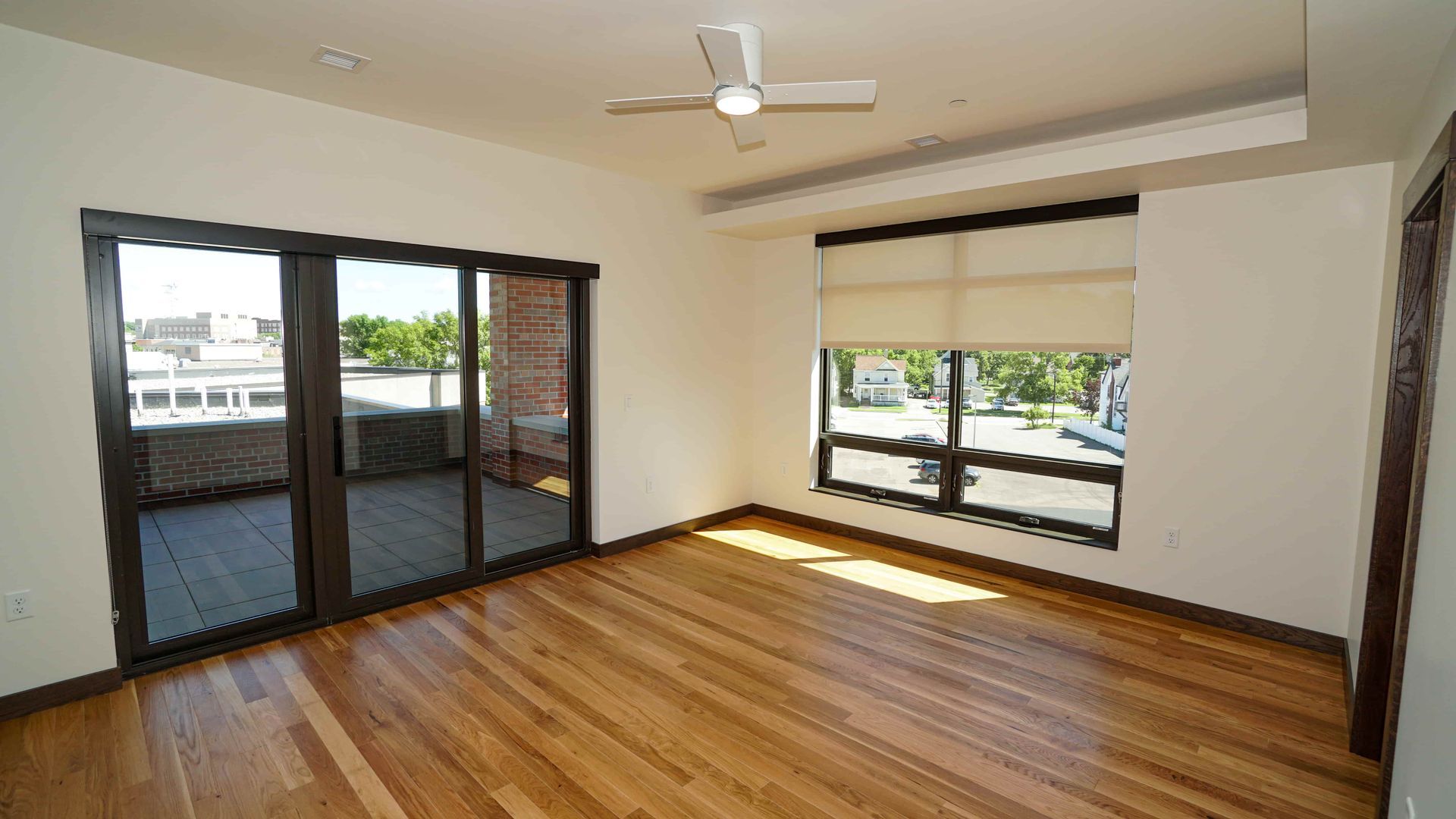 An empty room with hardwood floors and a ceiling fan.