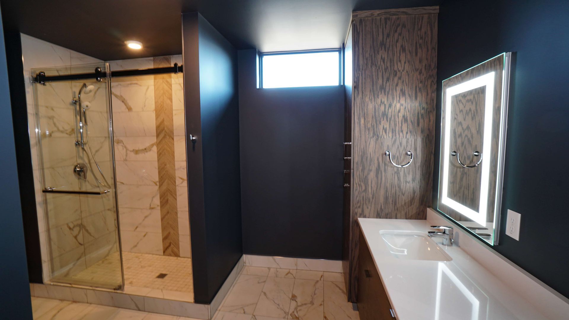 A bathroom with a walk in shower , sink and mirror.