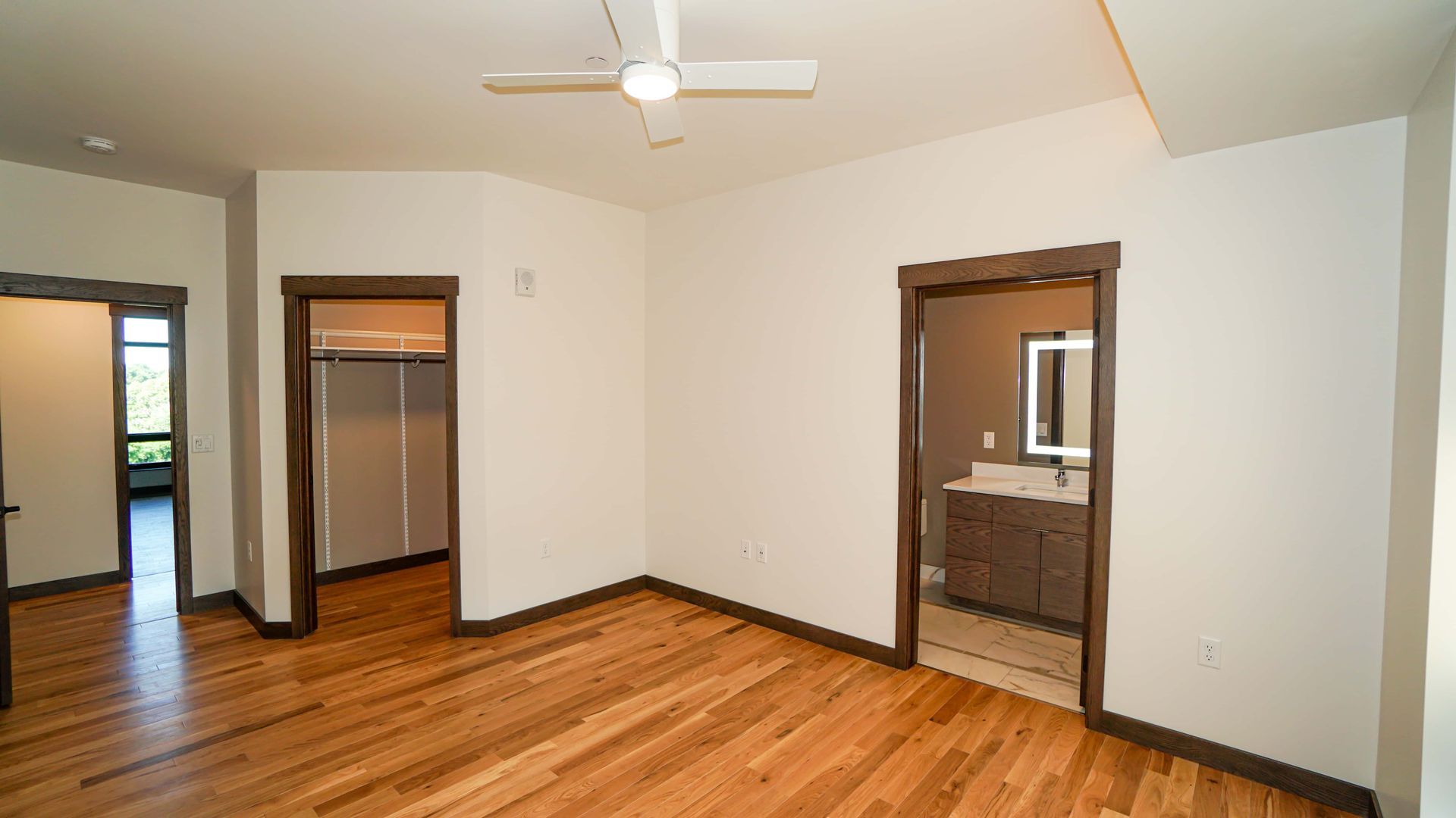 An empty room with hardwood floors and a ceiling fan.