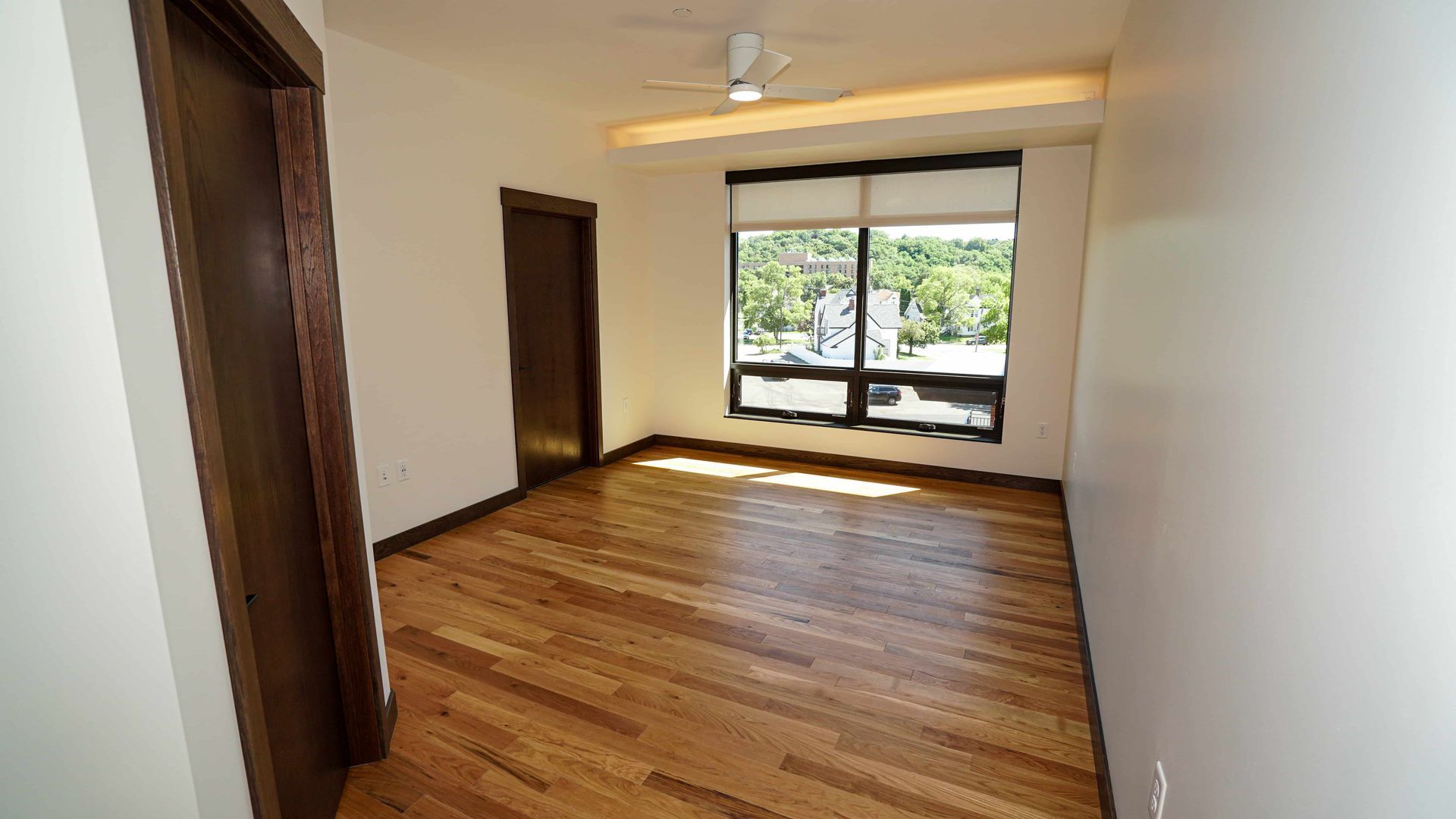 An empty room with hardwood floors and a ceiling fan