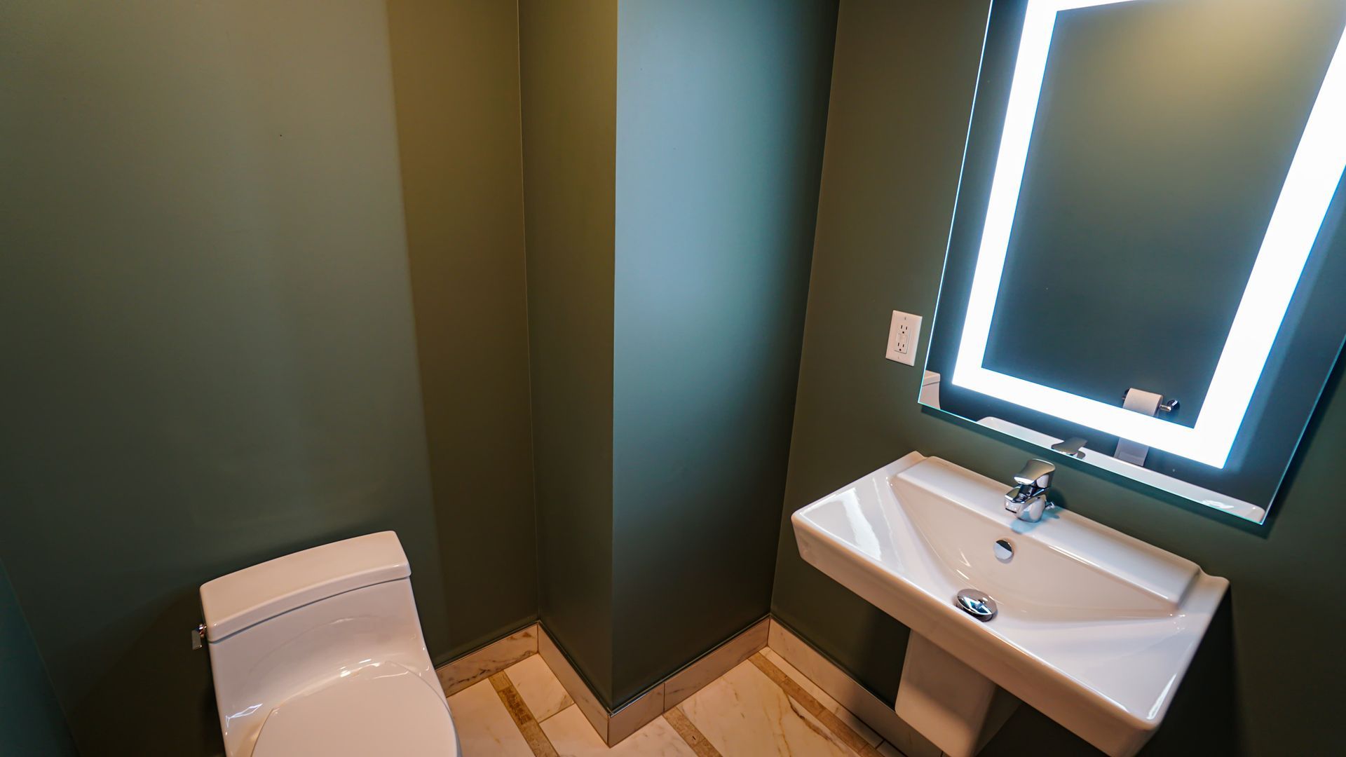 A bathroom with a toilet , sink and mirror.