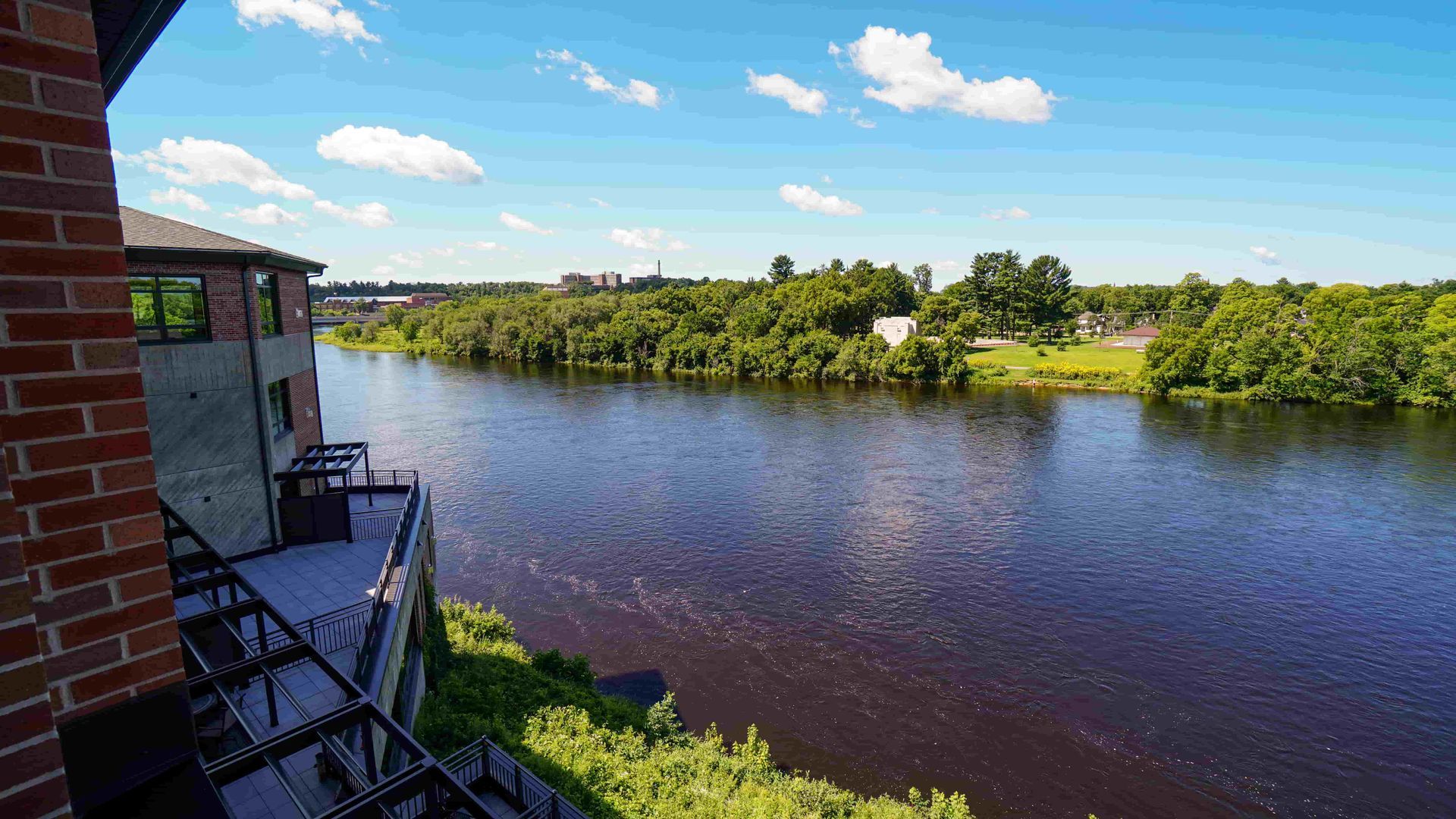 A large body of water is surrounded by trees and a brick building.