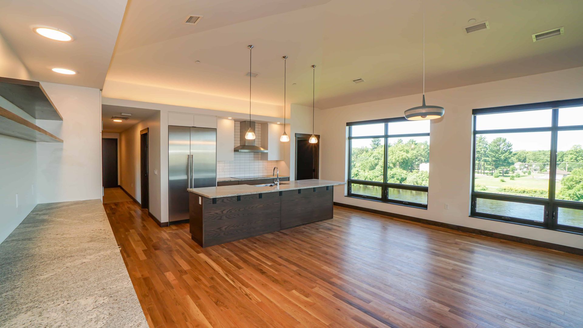 An empty kitchen with hardwood floors and a large island in the middle of the room.