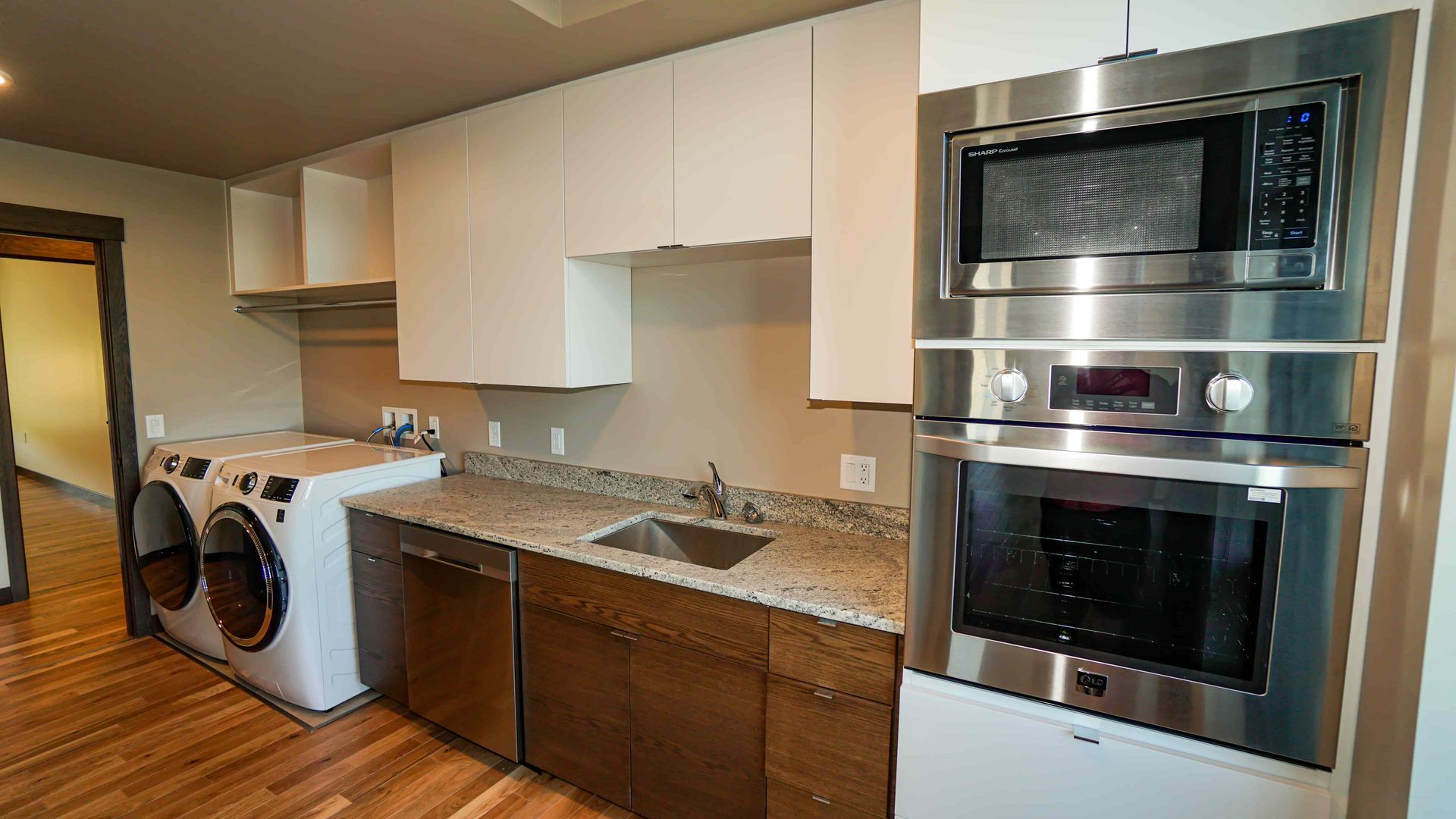 A kitchen with stainless steel appliances , a washer and dryer , a sink , and a microwave.