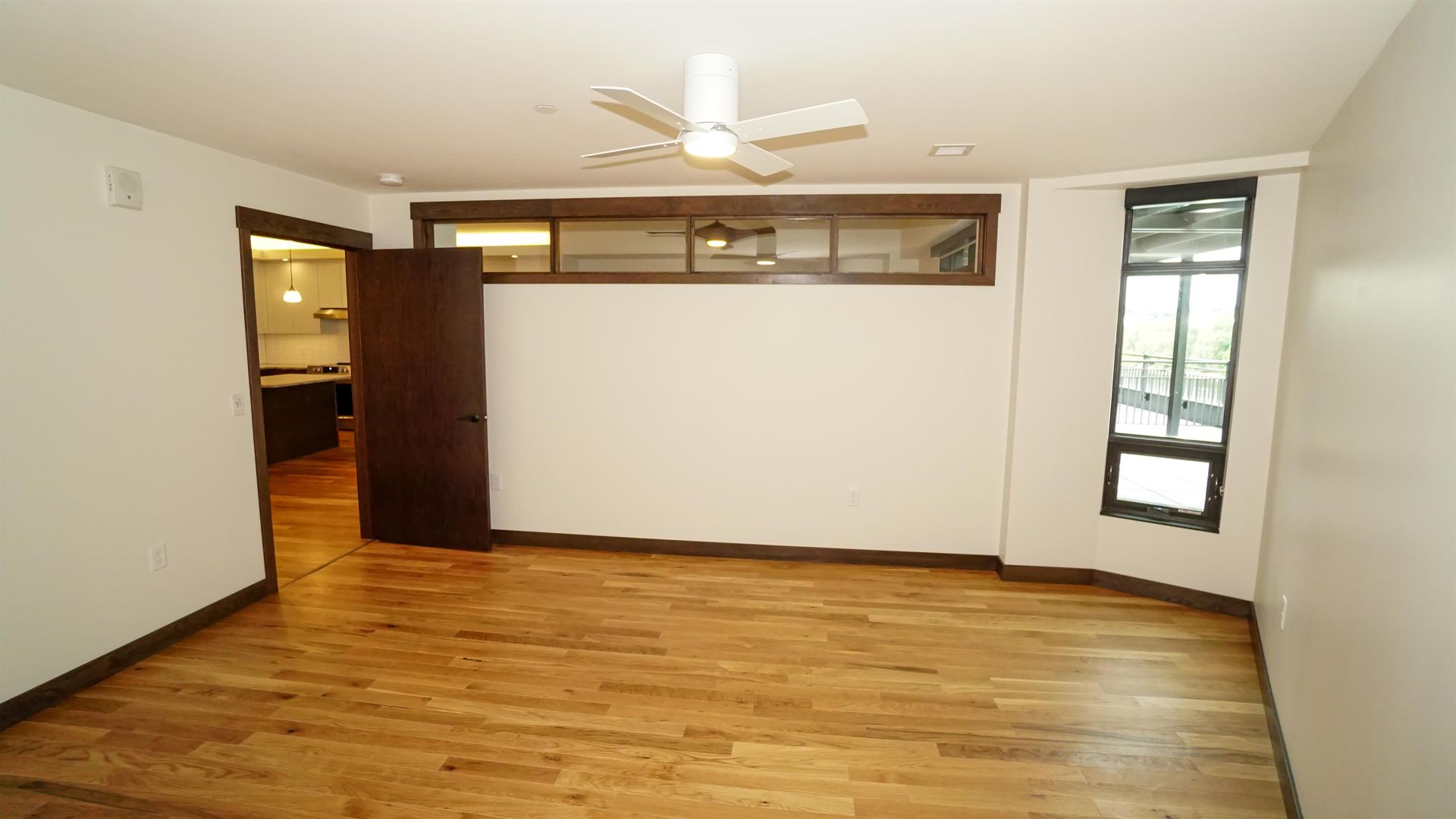 An empty room with hardwood floors and a ceiling fan.