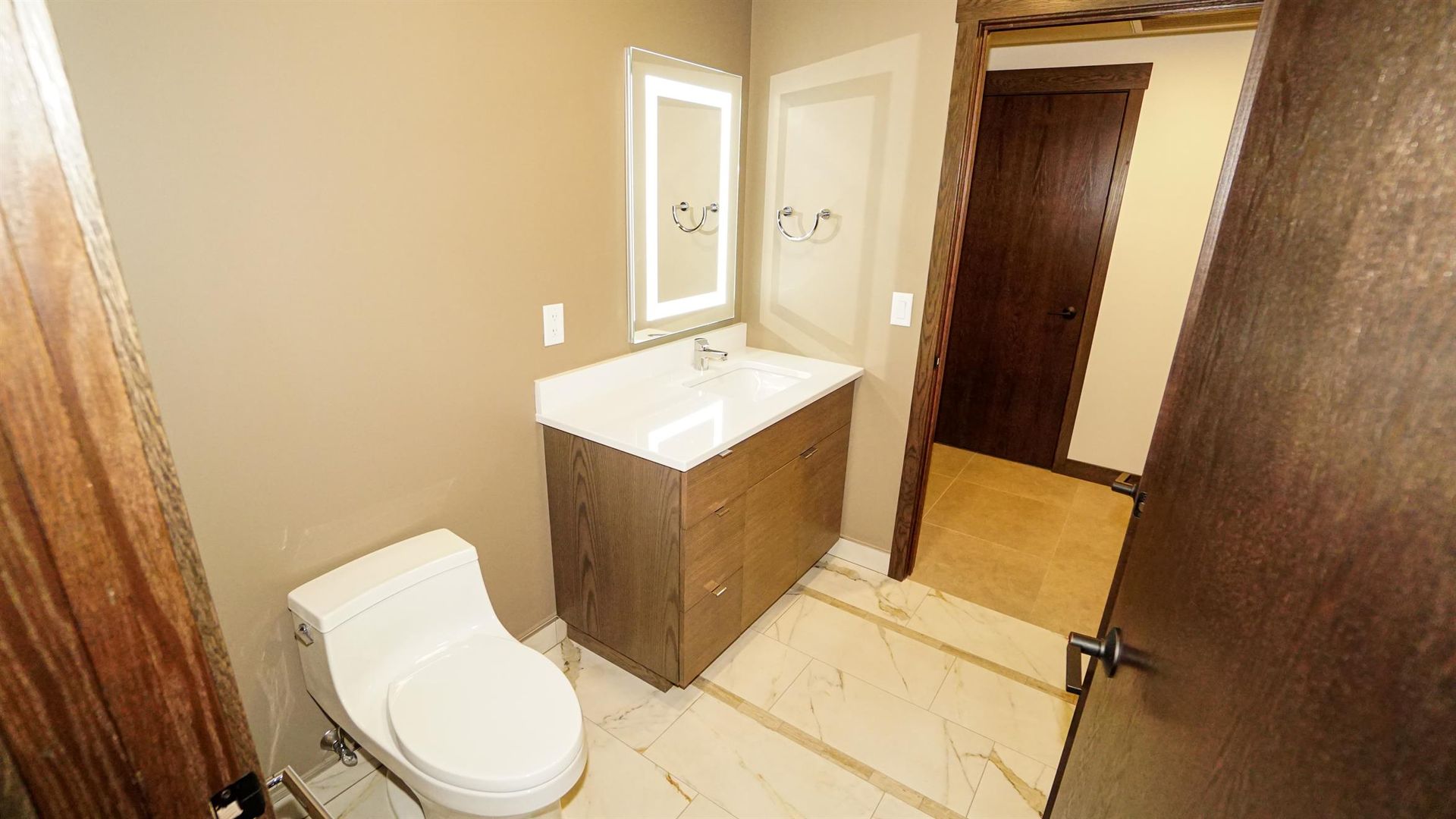 A bathroom with a toilet , sink and mirror.