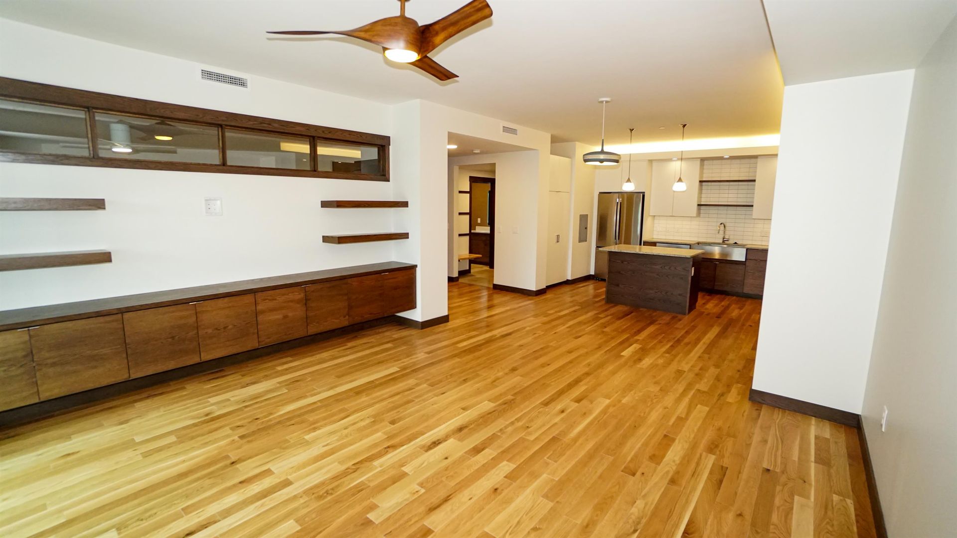 A living room with hardwood floors and a ceiling fan.