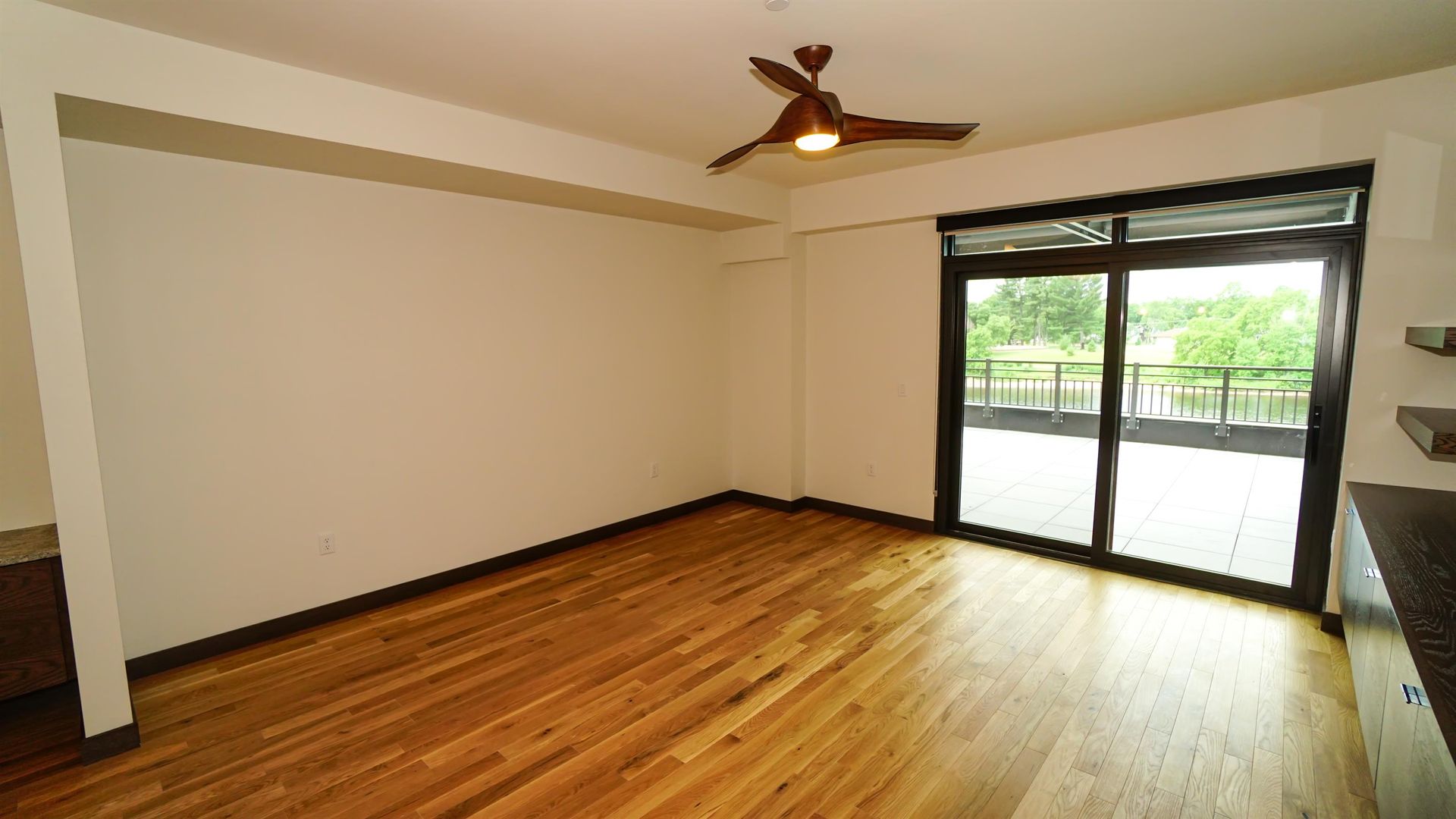 An empty living room with hardwood floors and a ceiling fan.