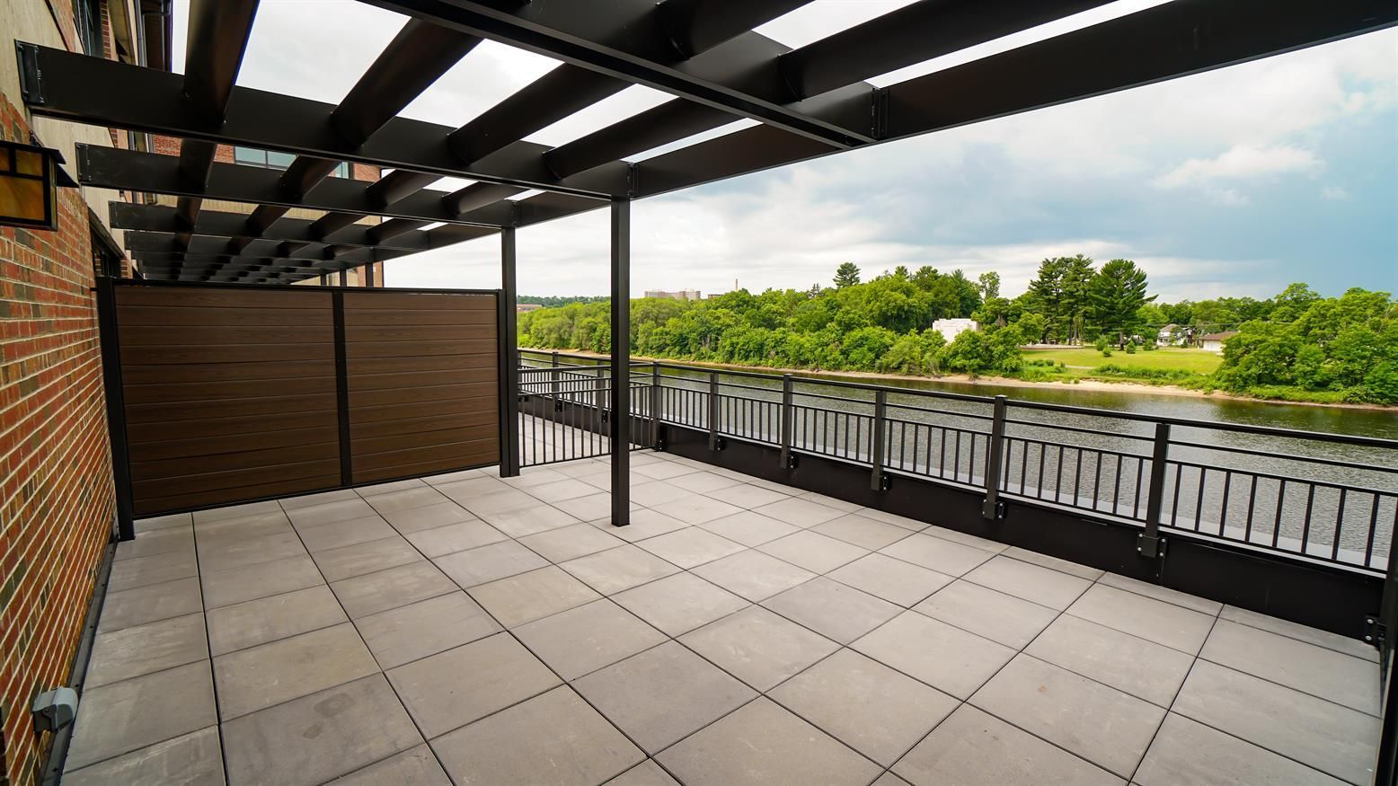 An empty balcony with a pergola overlooking a river.