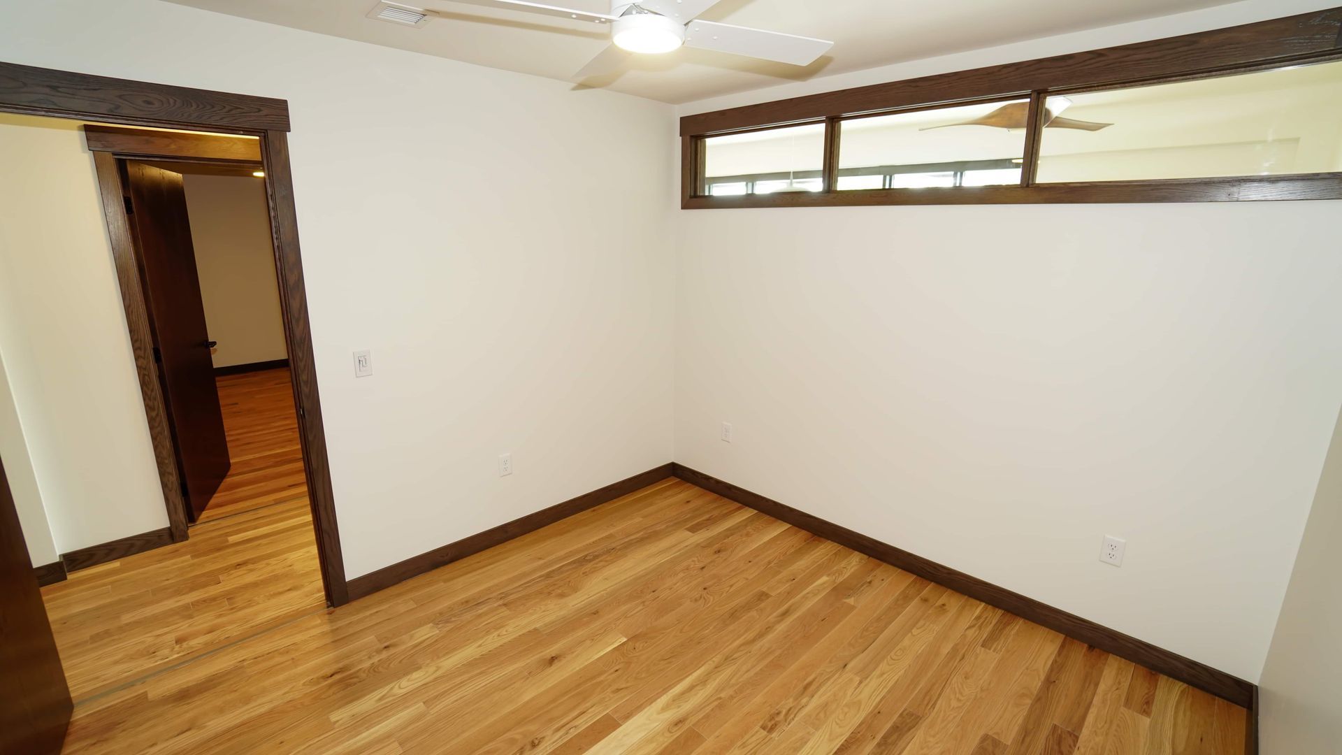 An empty room with hardwood floors and a ceiling fan.