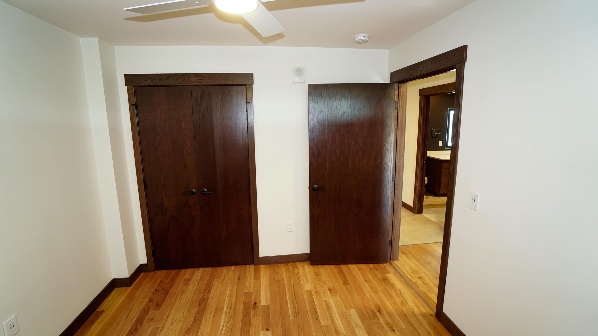 An empty bedroom with hardwood floors and a ceiling fan.