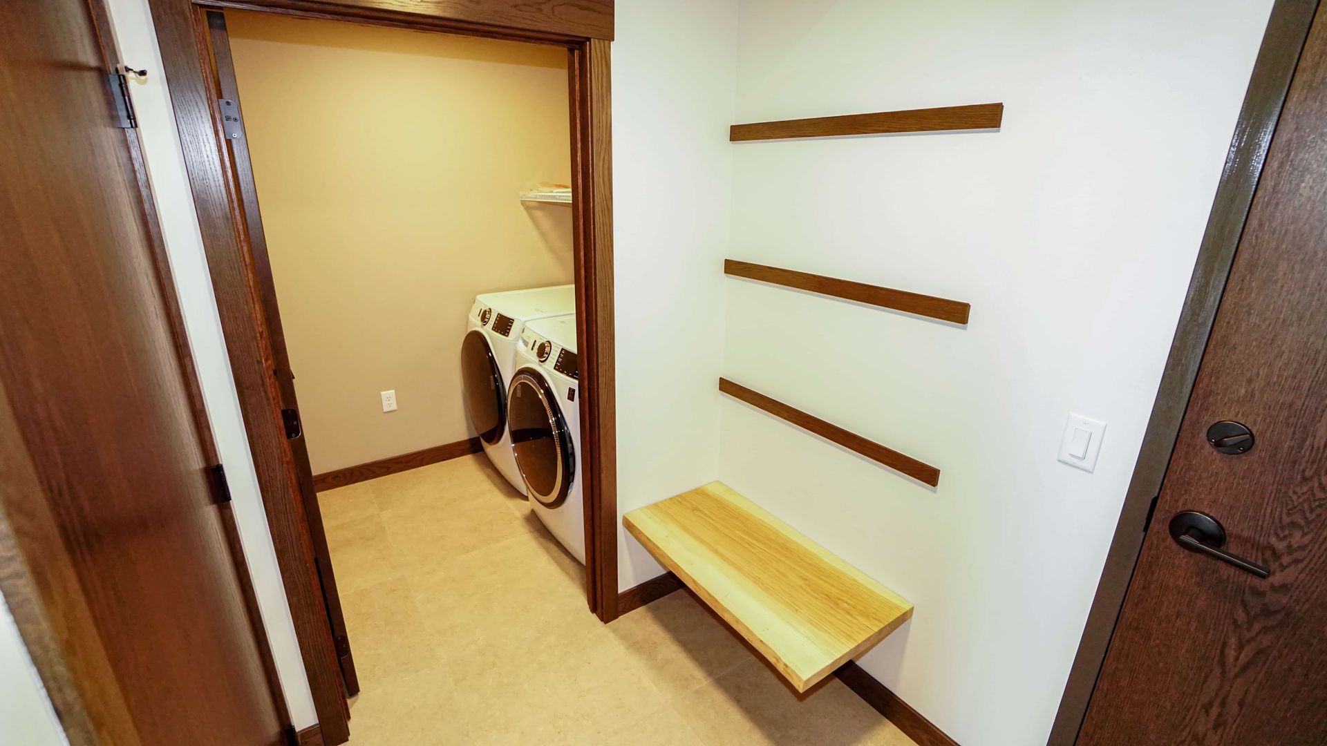 A laundry room with a washer and dryer and a wooden bench.