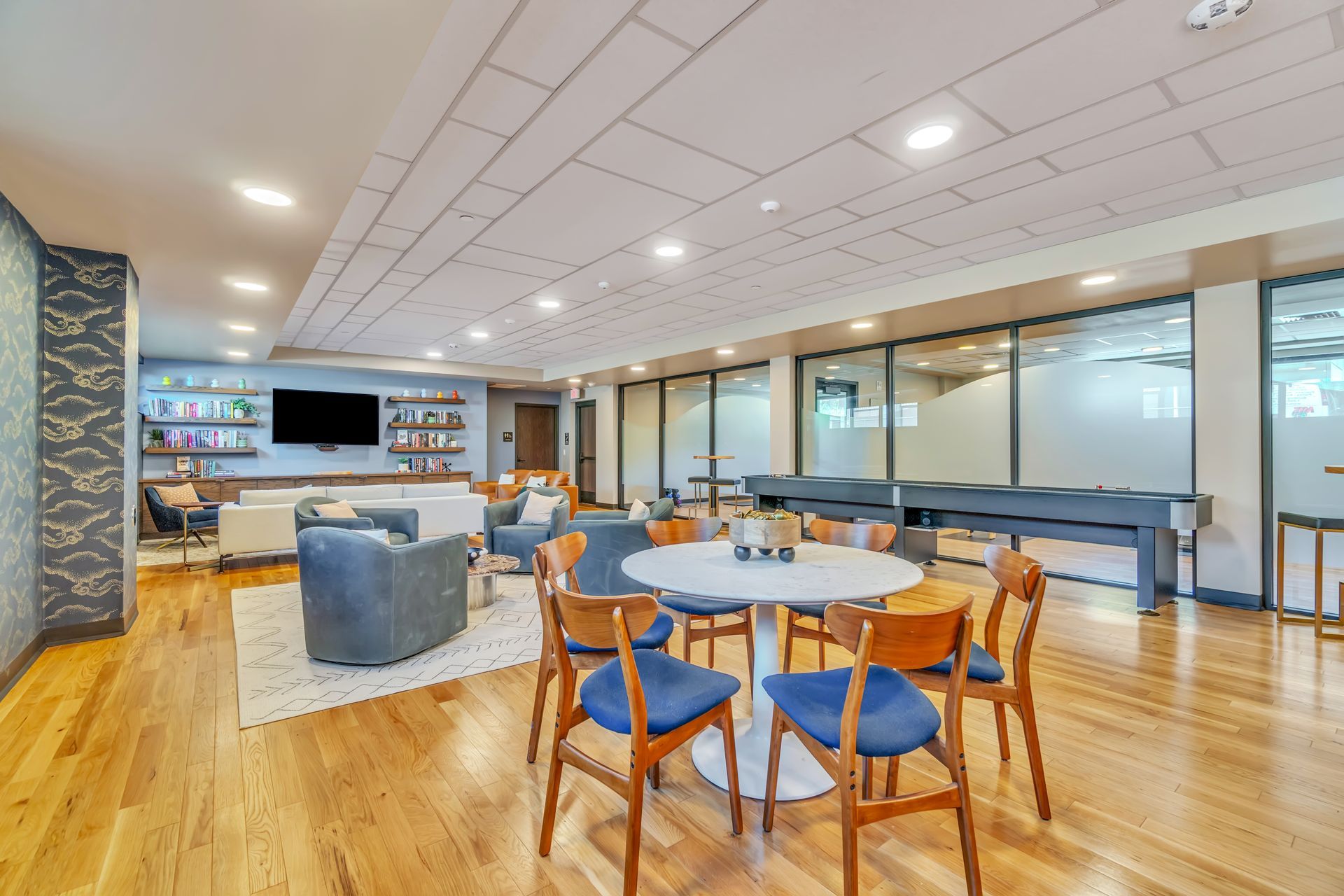 Lounge with wooden floors, round table with chairs, and seating area with a TV.