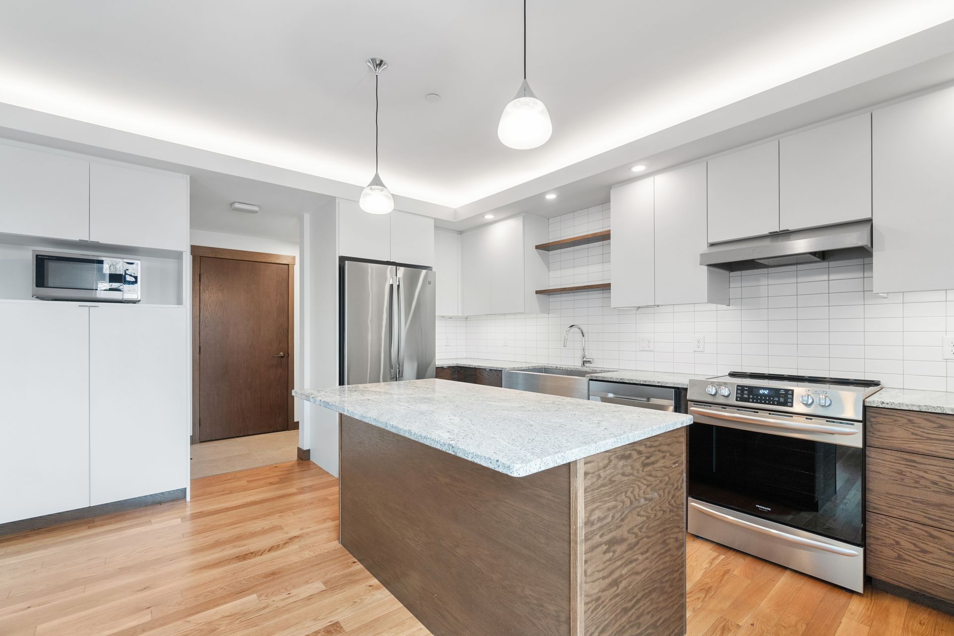 Modern kitchen with white cabinets, stainless steel appliances, and a wood island.