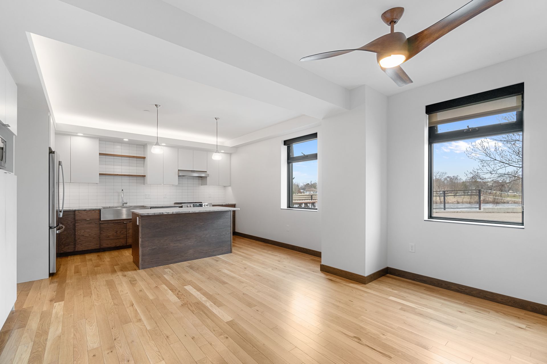 Modern apartment interior with open kitchen, hardwood floors, and large windows.