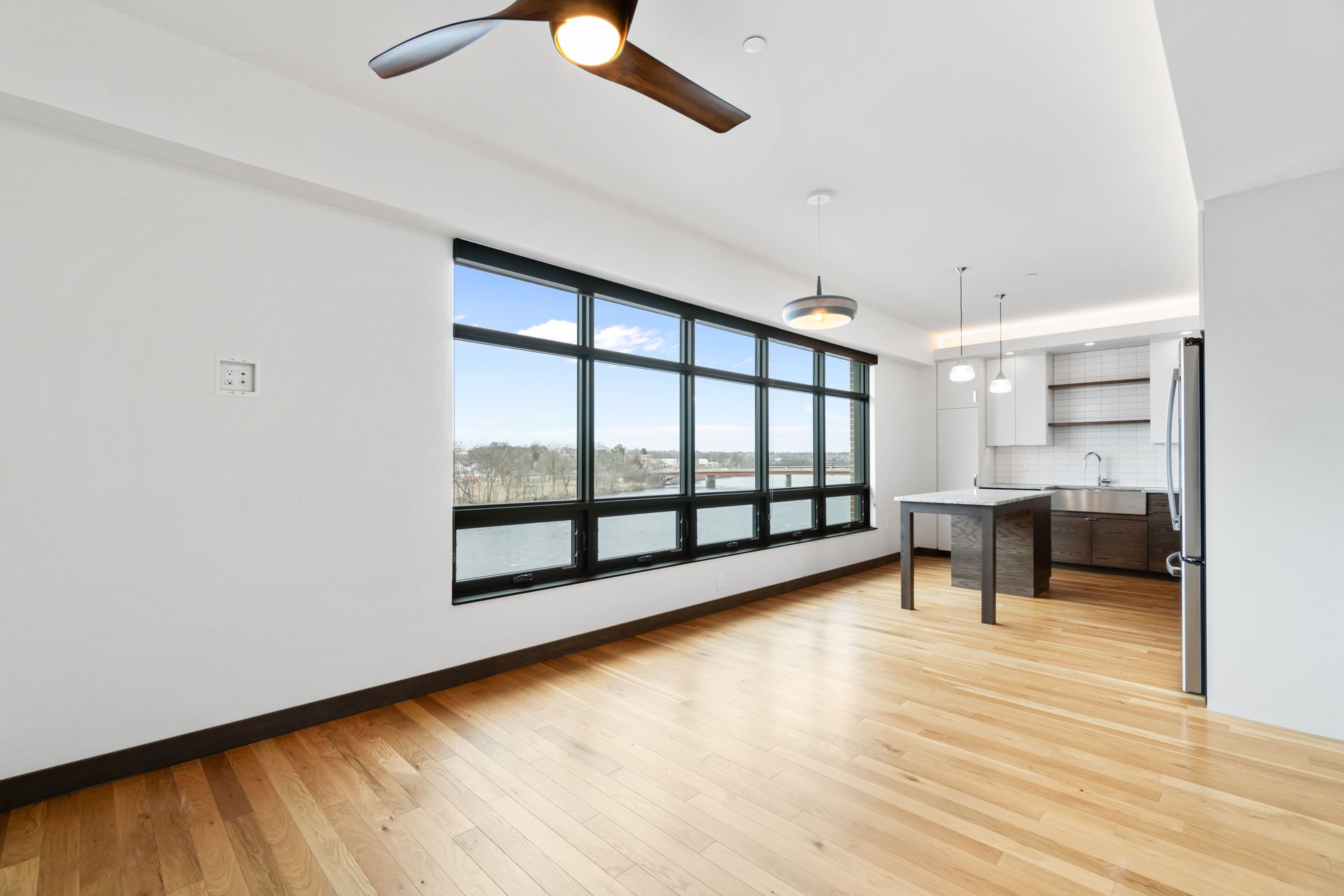 Bright, modern apartment interior with hardwood floors, large window, and open kitchen.