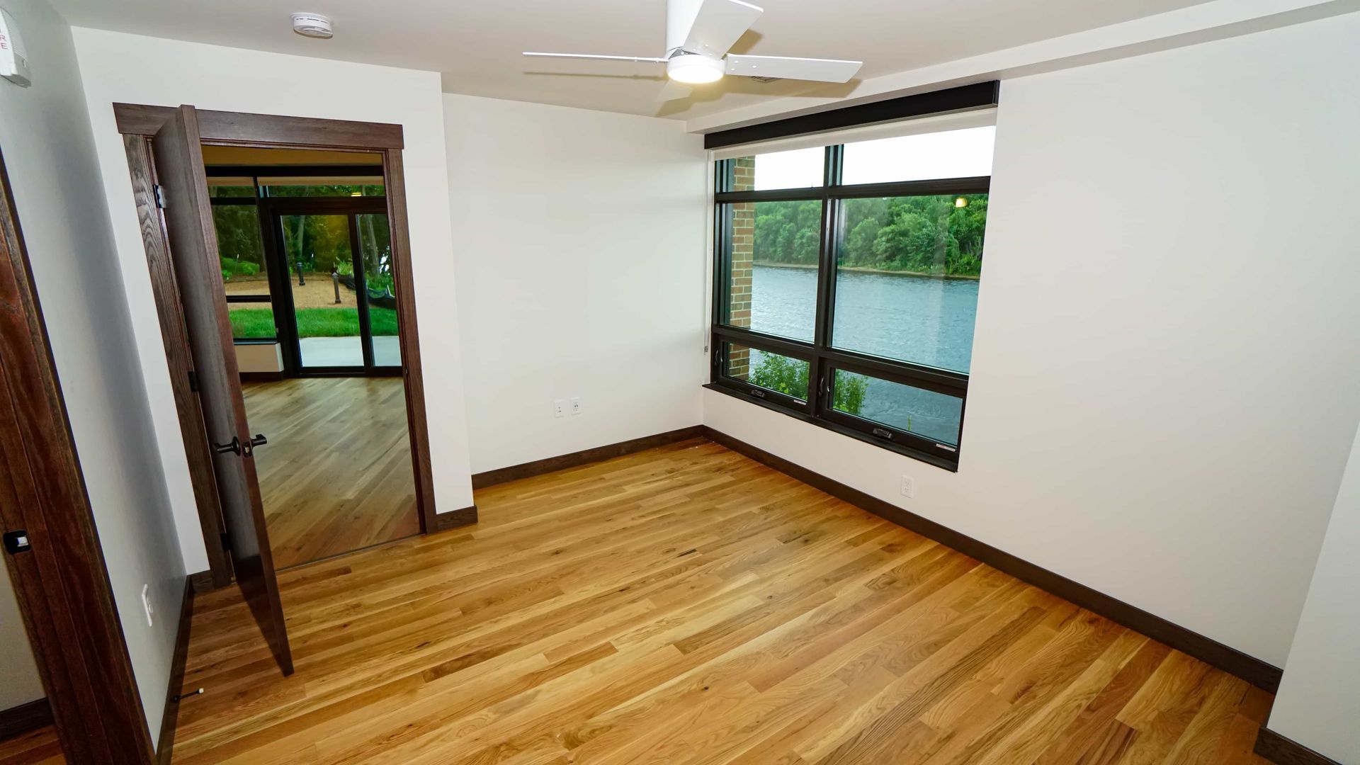 An empty room with hardwood floors and a ceiling fan.