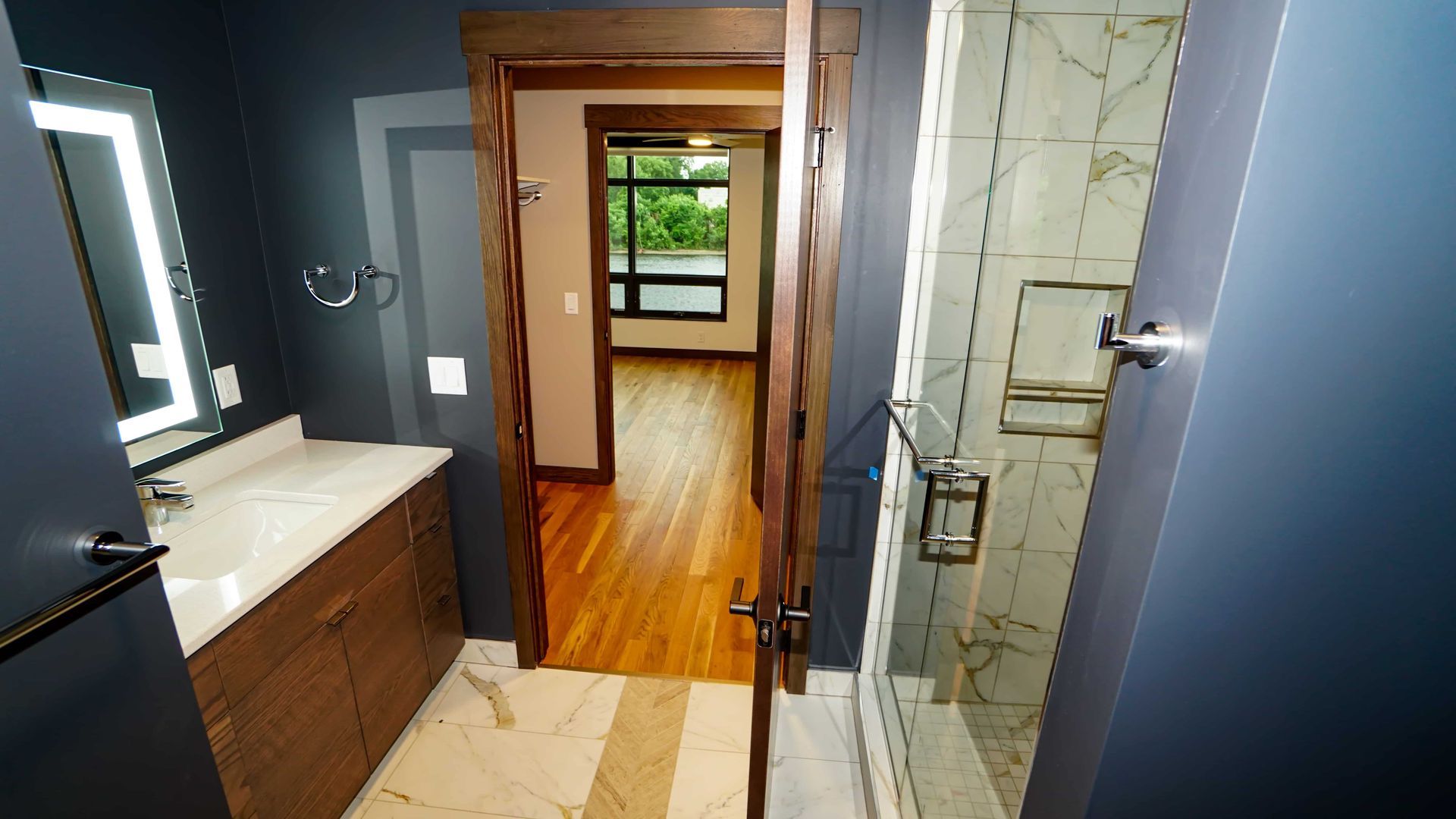 A bathroom with a sink , mirror and walk in shower.