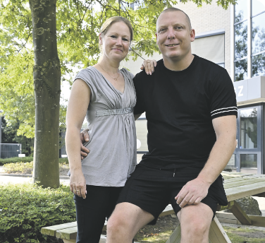 Een man en een vrouw poseren voor een foto terwijl ze op een picknicktafel zitten