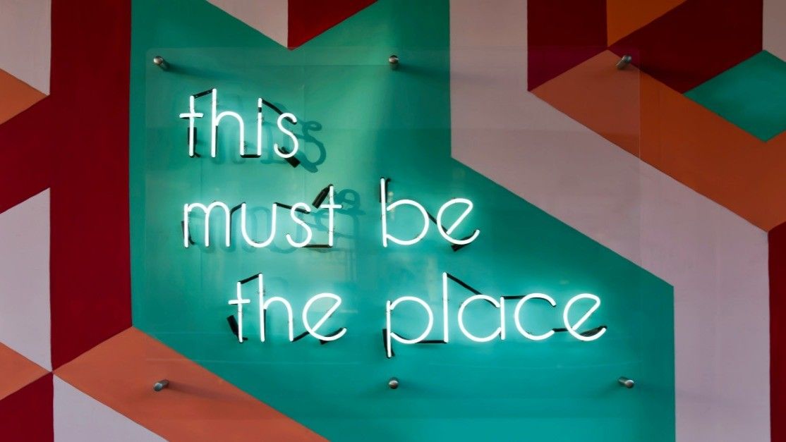 Neon sign on a teal wall reads 