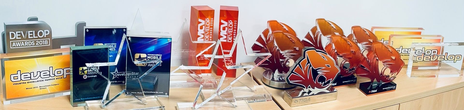 Various glass awards displayed on a wooden surface, showcasing colors like orange, blue, and gold.