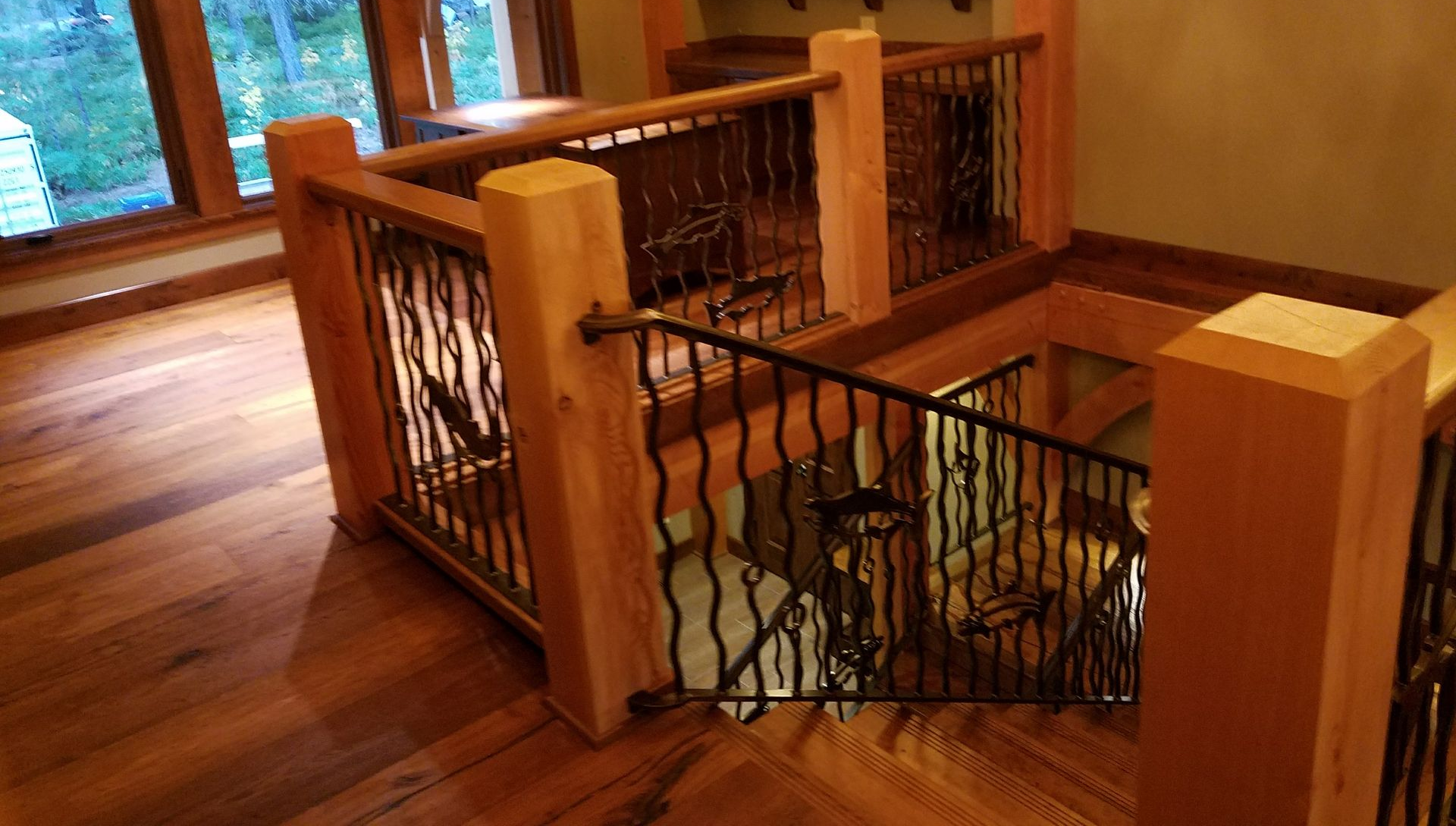 Staircase with wooden posts and wrought iron railings; hardwood floors.