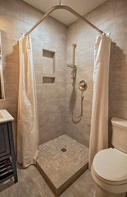Small, tiled shower with curved curtain rod, and toilet on the right.