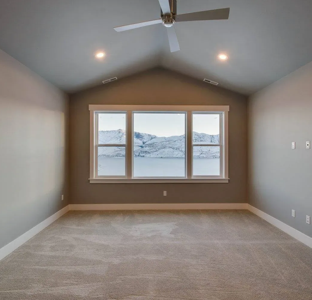 Empty bedroom with a window looking out onto a snowy mountain landscape.