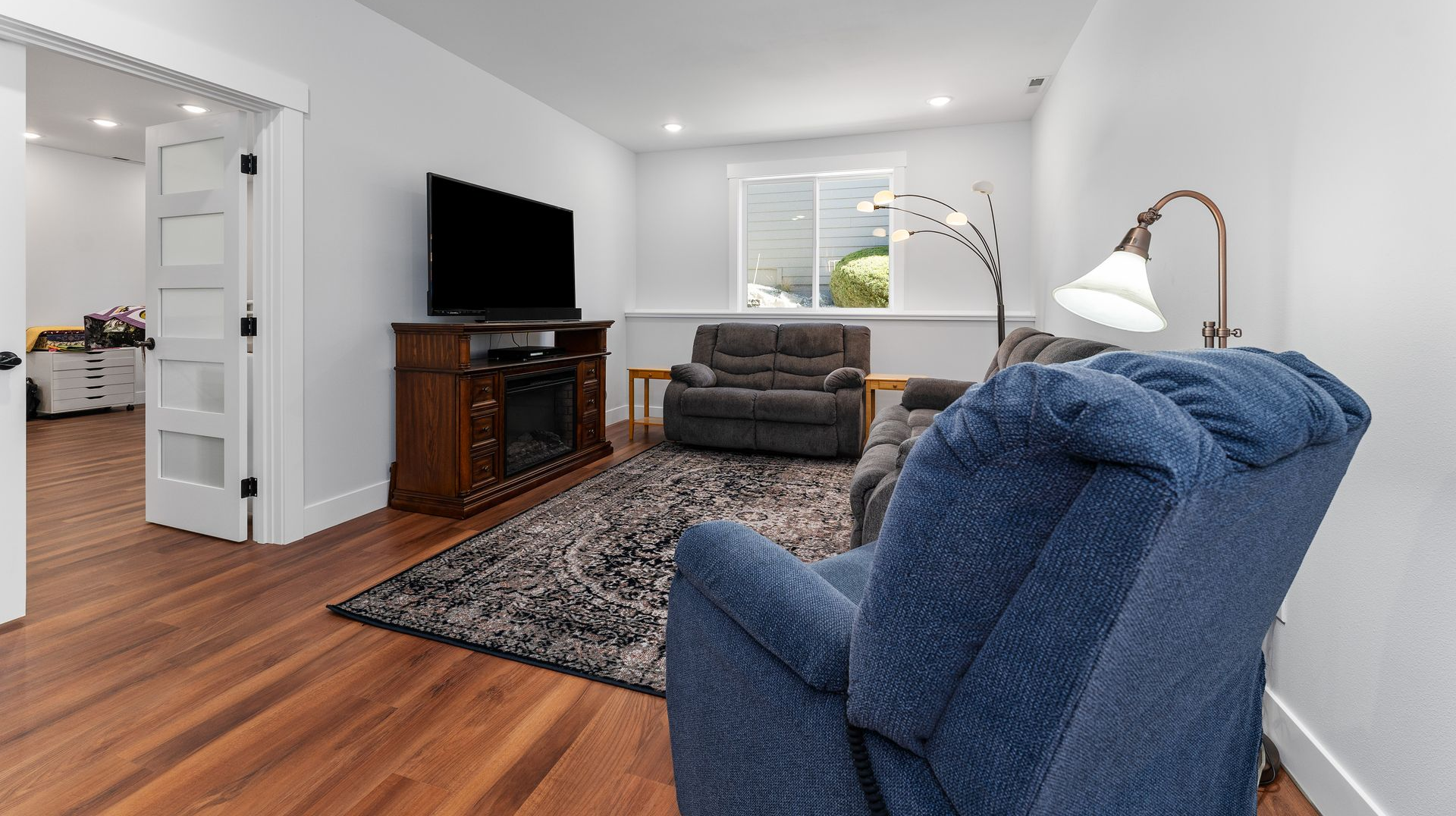 Living room with TV, recliner, rug, and open door to another room.
