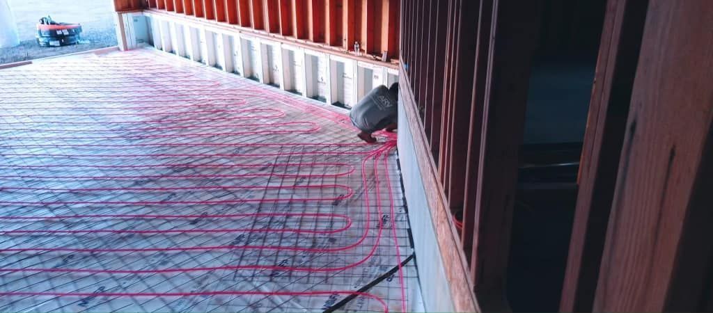 A person is working on a concrete floor in a building under construction.