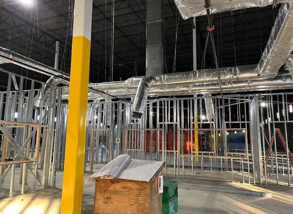 A large building under construction with a yellow pole in the middle.