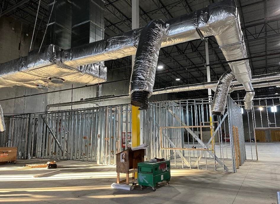A large warehouse under construction with a lot of pipes coming out of the ceiling.