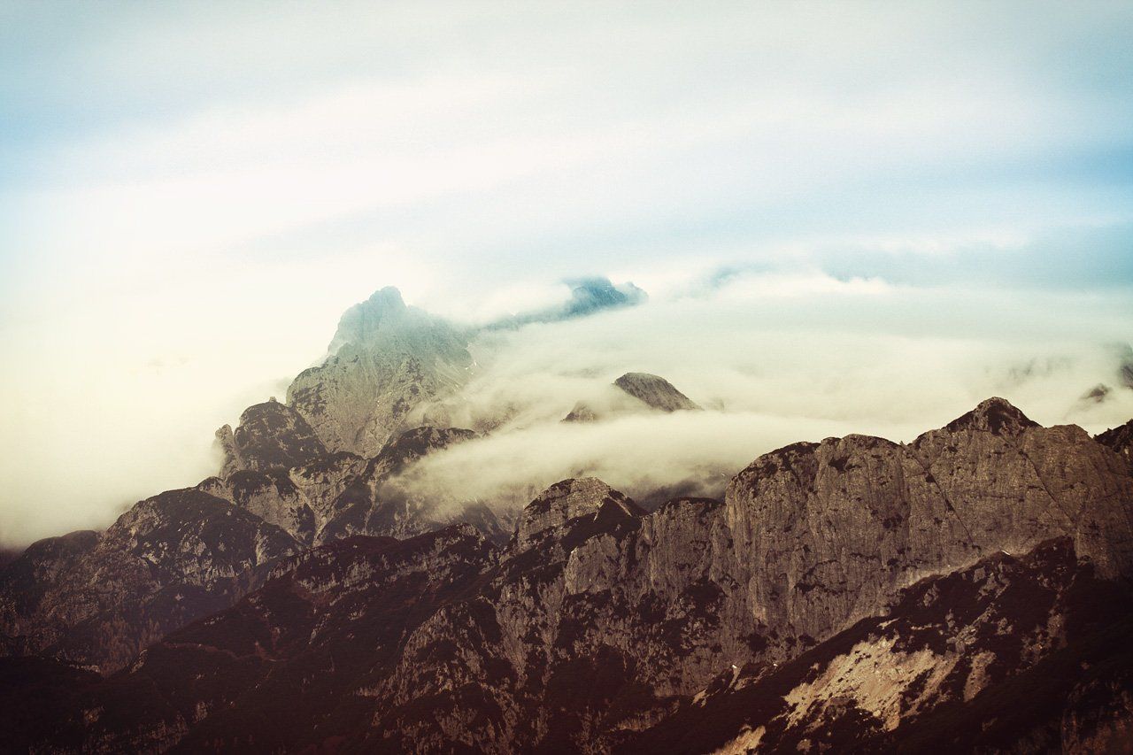 A mountain covered in clouds with a blue sky in the background.