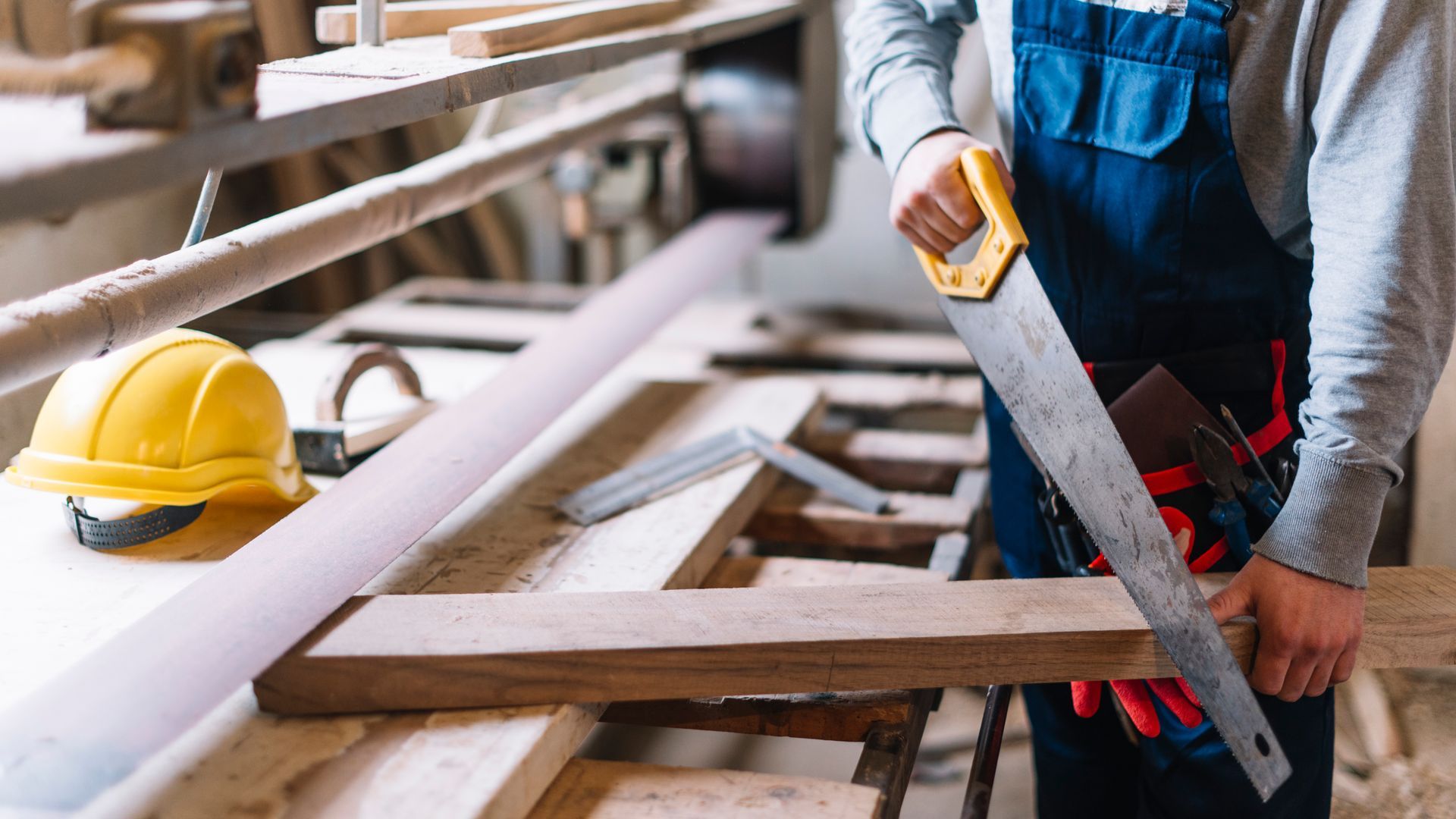 A man is cutting a piece of wood with a saw.