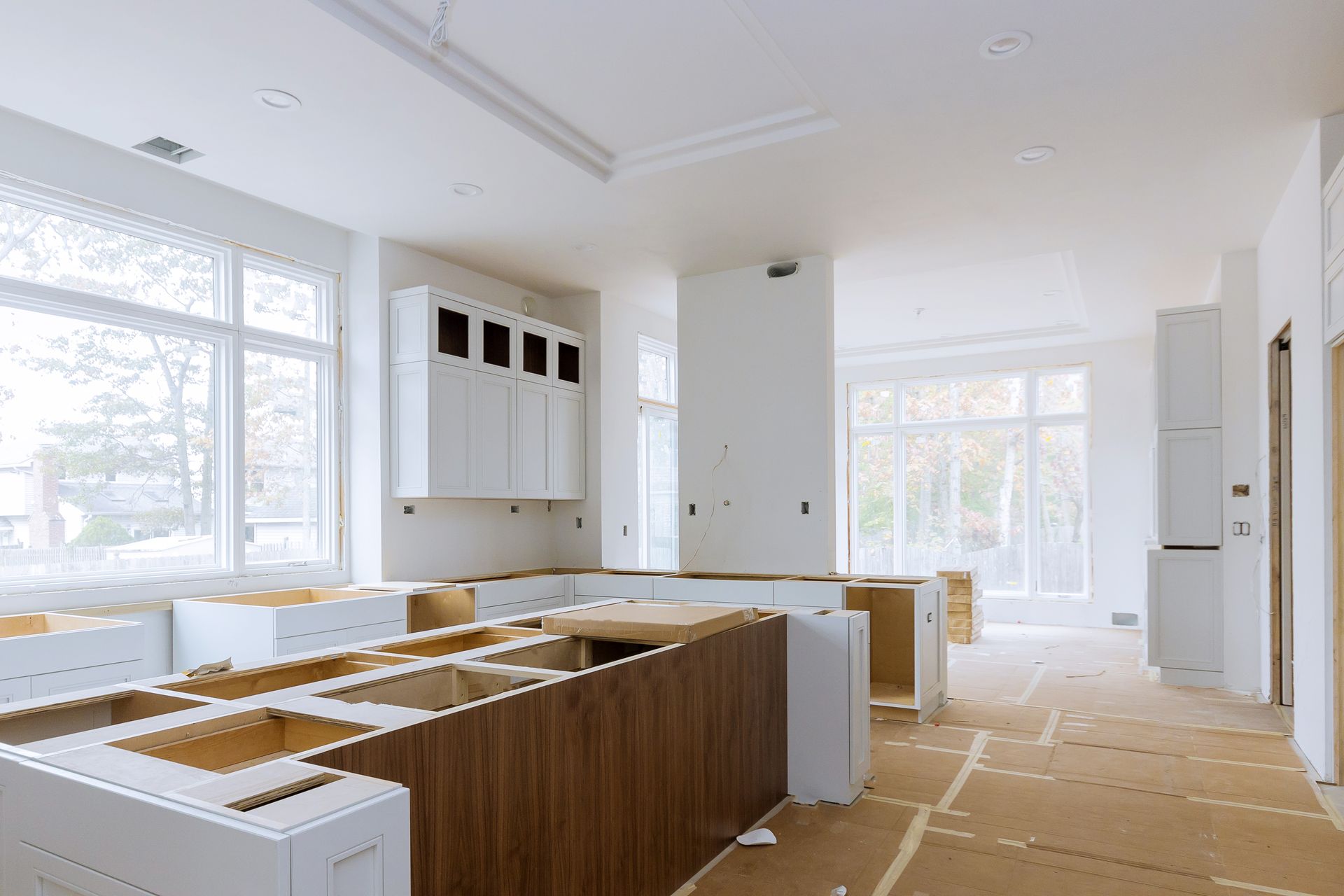 A kitchen under construction with white cabinets and wooden counter tops.