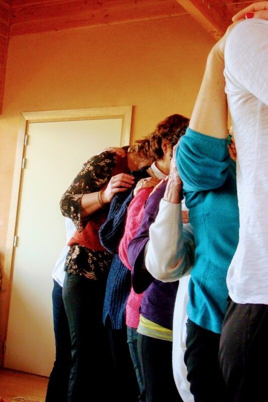 Des gens alignés, les têtes se touchant, à l'intérieur. Pulls et hauts variés, porte blanche et mur orange en arrière-plan.