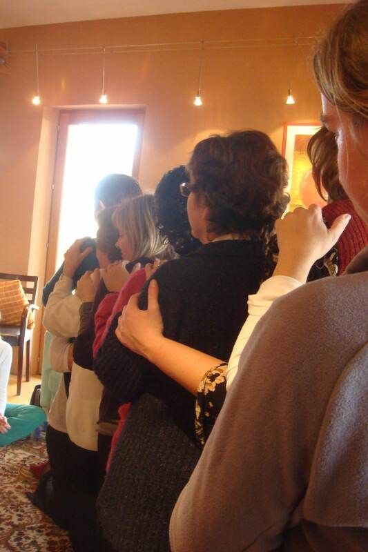 Des gens en groupe serré, les bras les uns autour des autres, à l'intérieur, près d'une fenêtre.