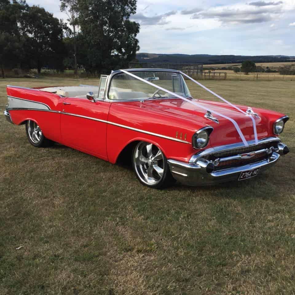 A Red Car With White Ribbons on the Windshield is Parked in a Grassy Field — ARB Budget Tyres in Delacombe, VIC