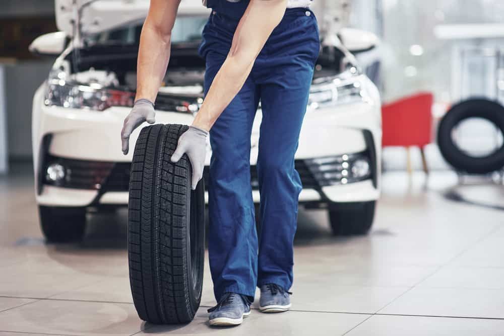 A Man is Holding a Tyre in Front of a Car — ARB Budget Tyres in Delacombe, VIC