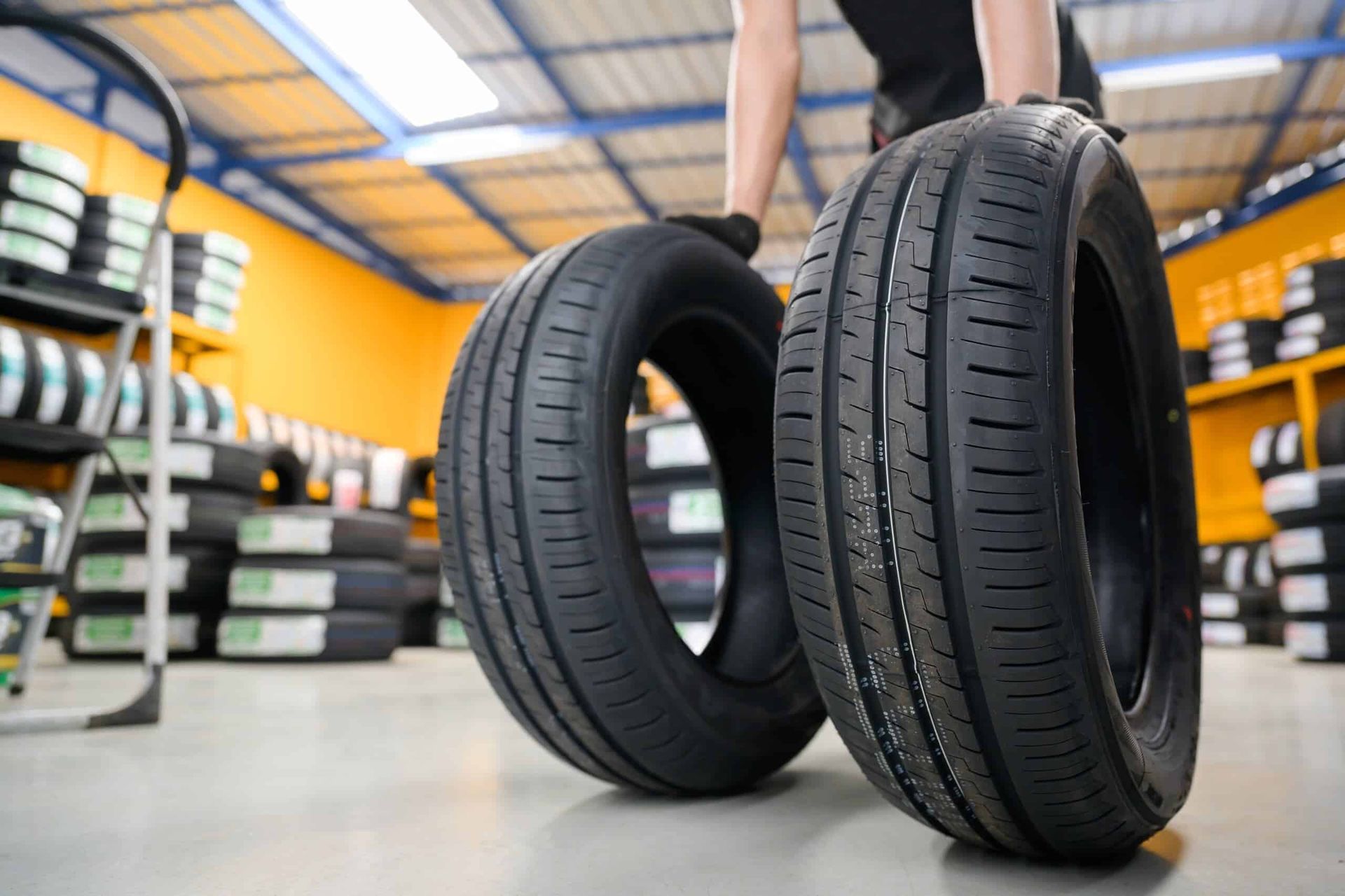 A Person is Holding Two Tyres in a Garage — ARB Budget Tyres in Delacombe, VIC