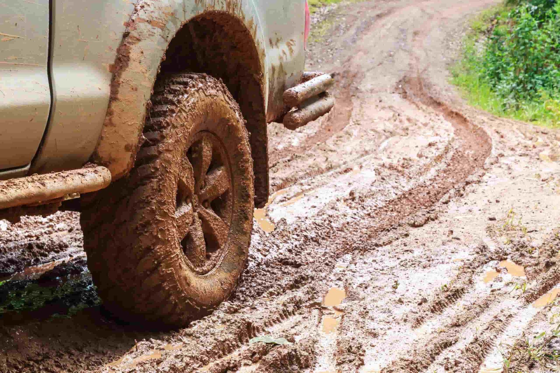 A Muddy Truck is Driving Down a Muddy Dirt Road — ARB Budget Tyres in Delacombe, VIC