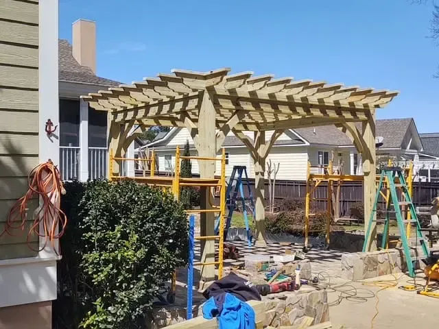A wooden pergola is being built in the backyard of a house.