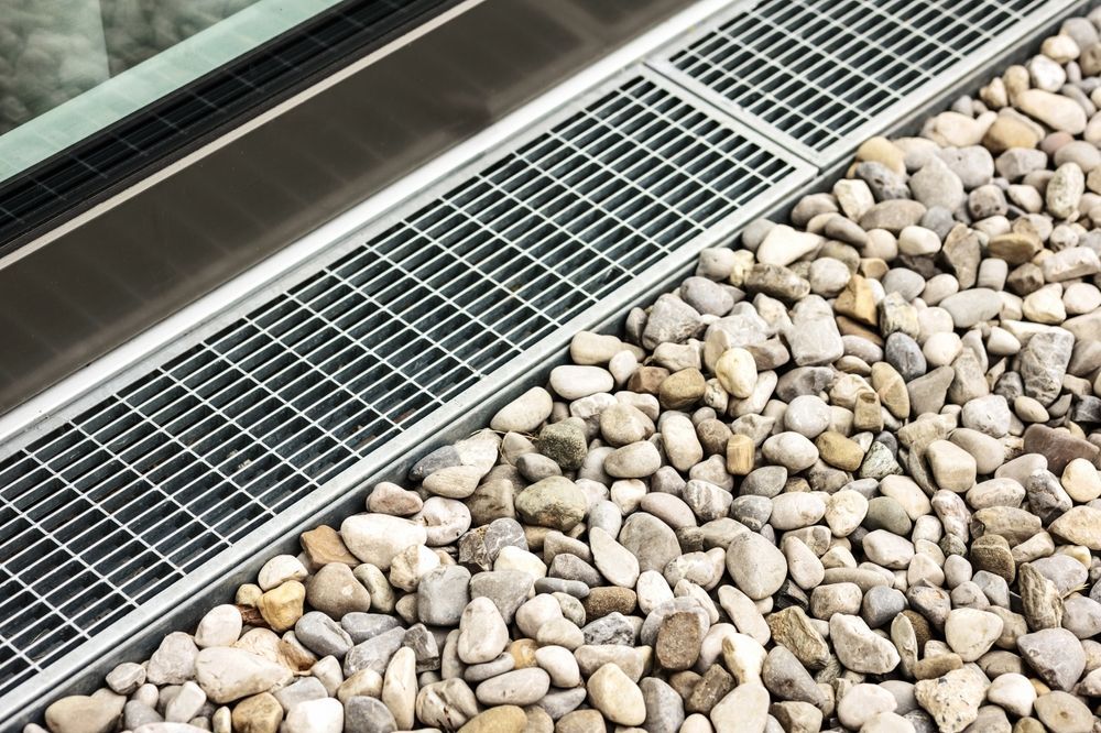 A metal grate is sitting on top of a pile of rocks.