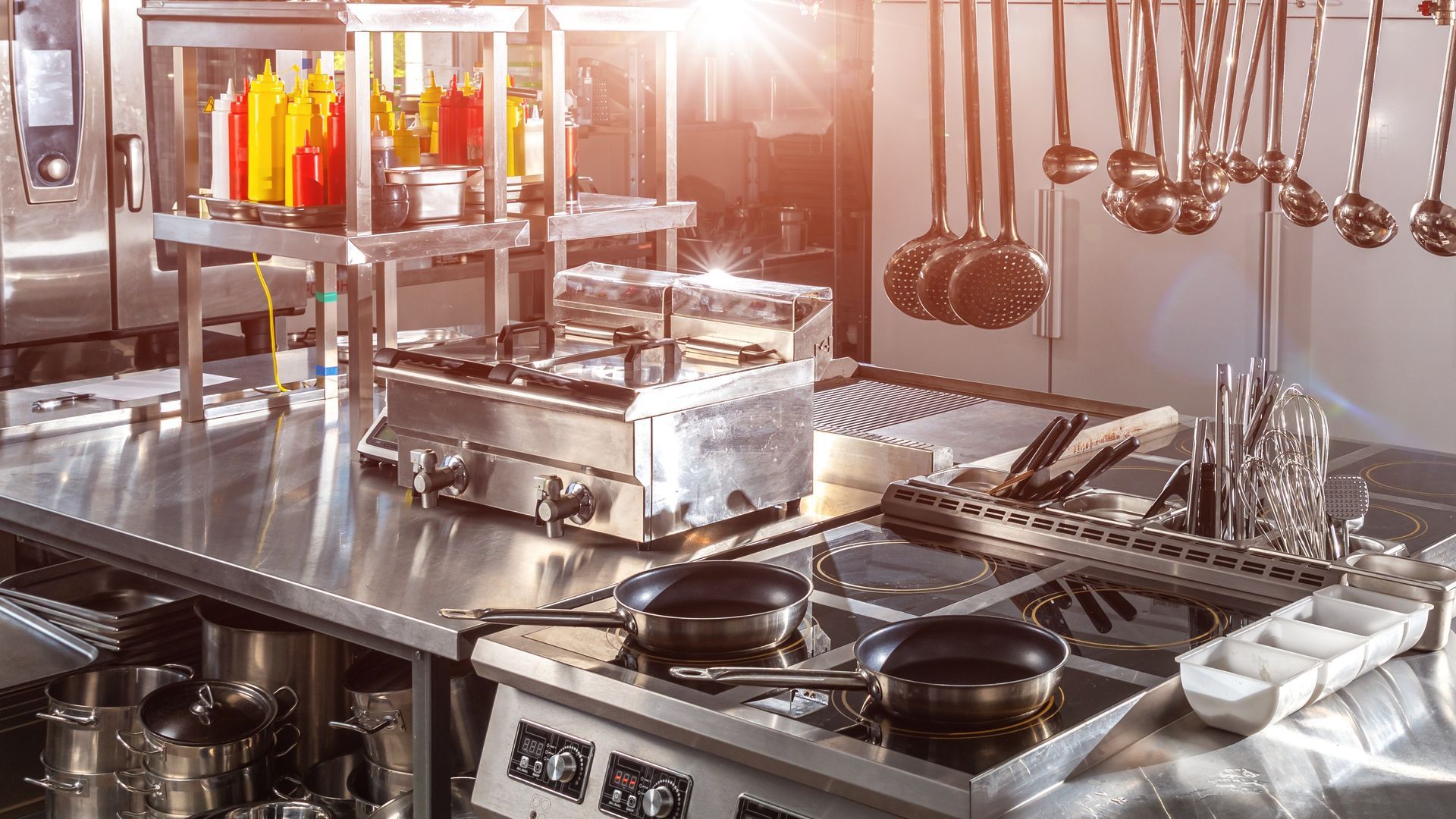 A kitchen with a lot of stainless steel appliances and pots and pans on the stove.