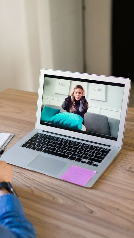 A woman is sitting on a couch talking to a doctor.