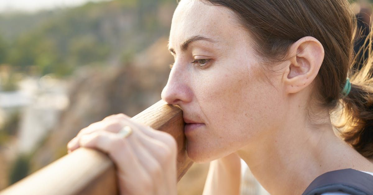 A woman is leaning on a railing looking out over a body of water.