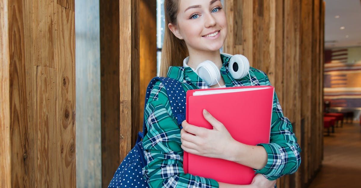 A young woman wearing headphones and a backpack is holding a red folder.